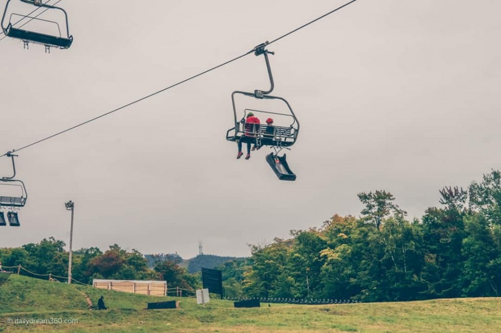 People on ski lift with luge hanging below at Tremblant