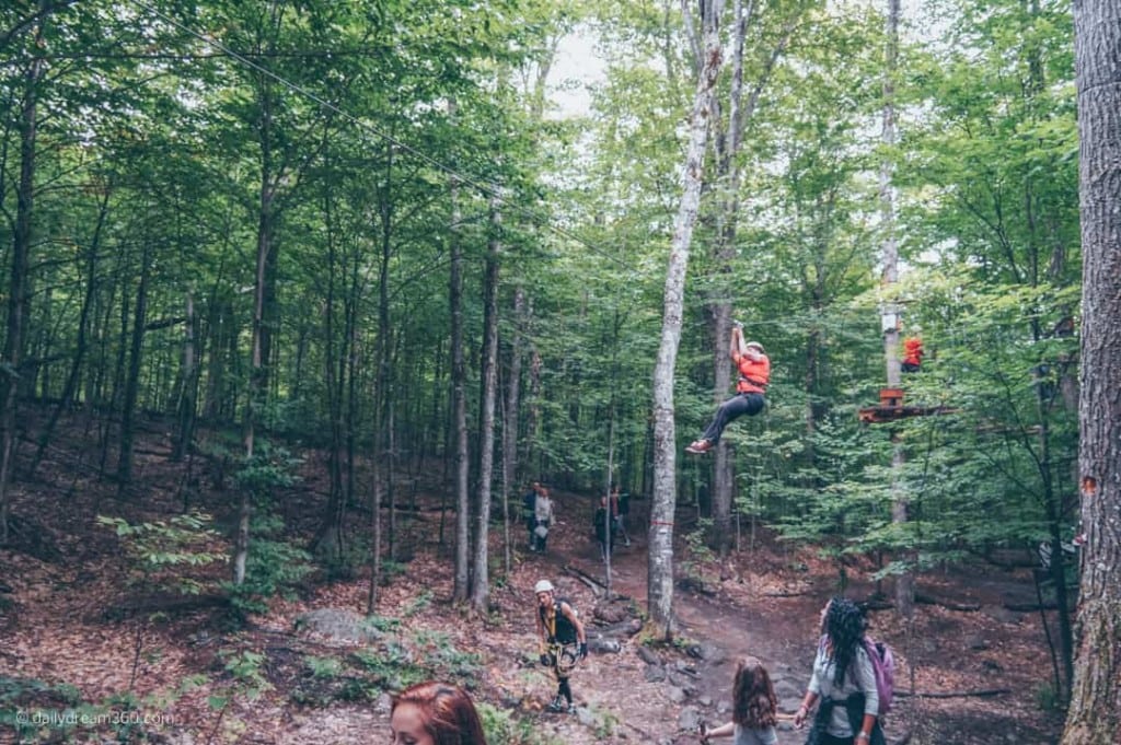 People zip lining with onlookers on trail below at Tremblant Resort