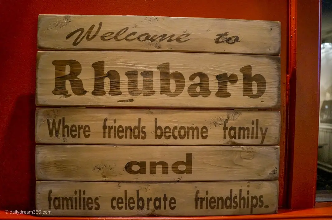 Sign at entrance to Rhubarb Restaurant reads Welcome to Rhubarb where friends become family and families celebrate friendships