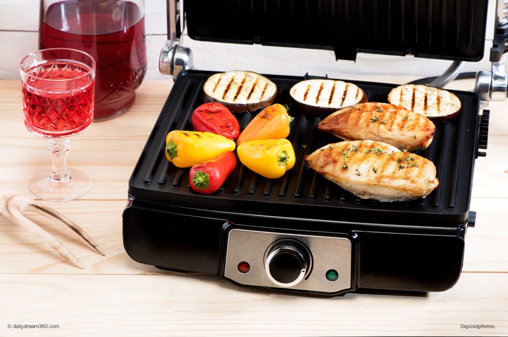 Indoor electric grill with chicken and vegetables cooking