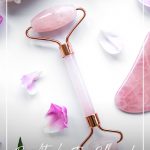 face roller on white table with flower petals and text Benefits of a Face Roller and Which Crystal Roller Should You Choose?