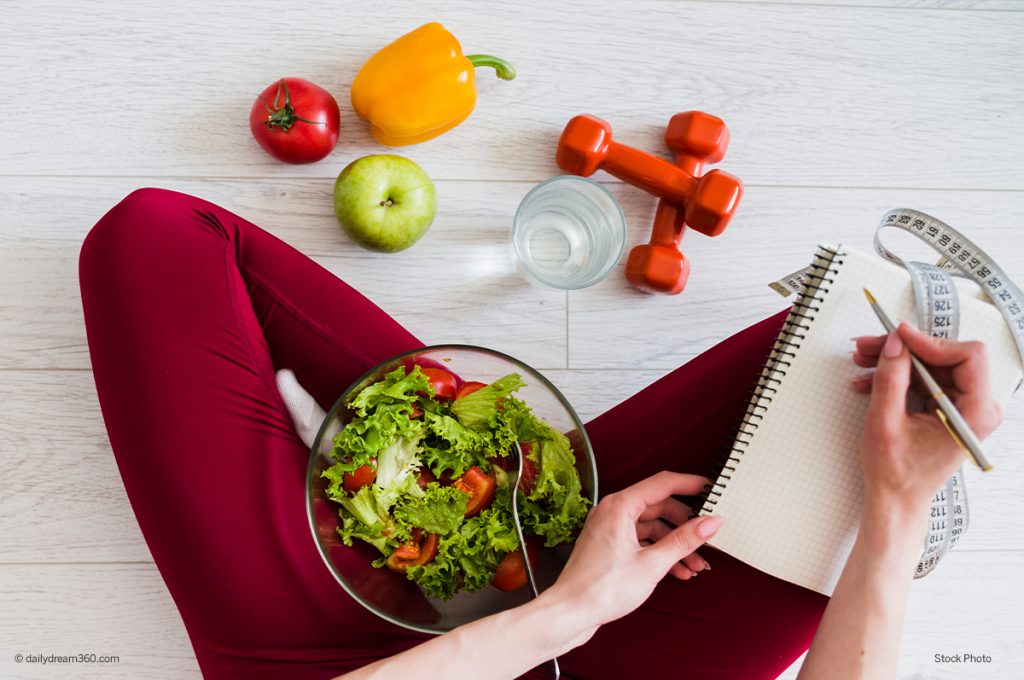 Woman with salad in lap taking notes