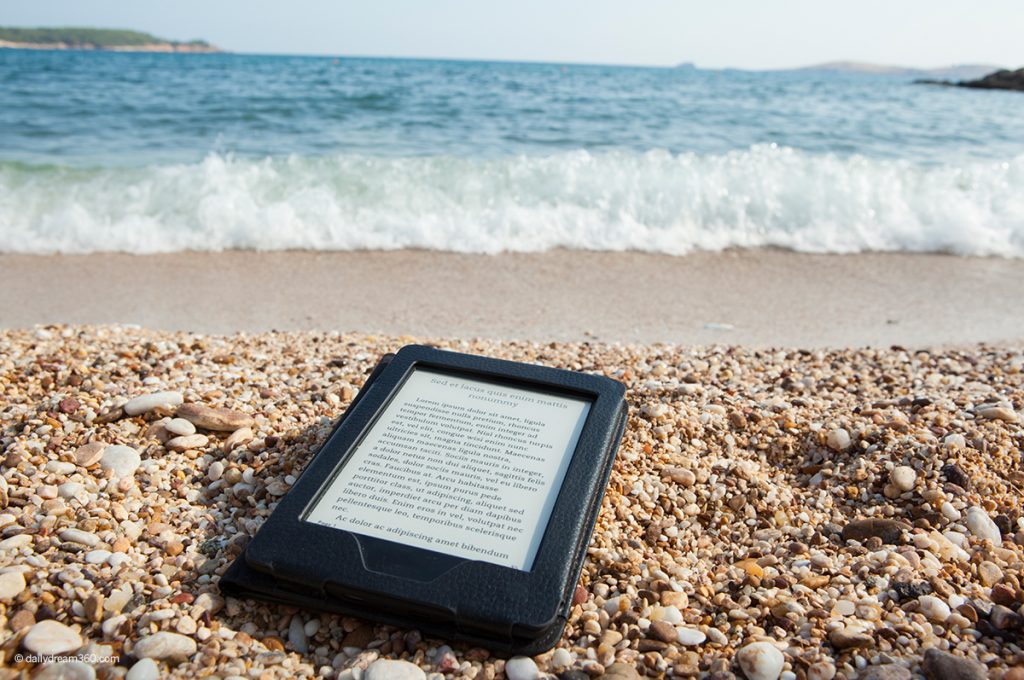 Ereader on beach with waves behind