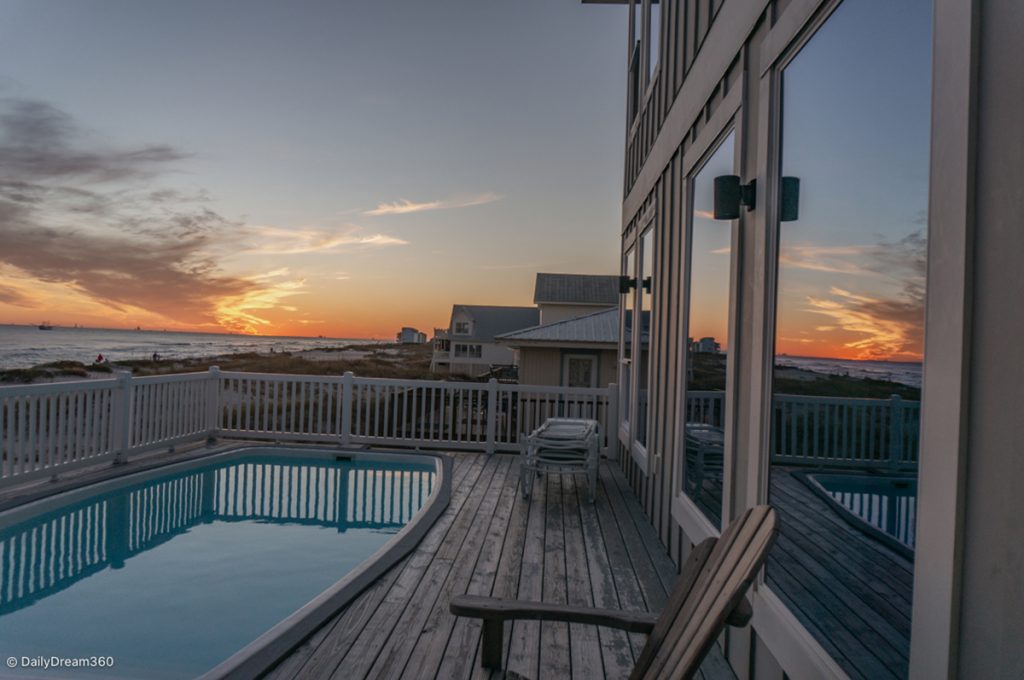 Sunset reflected on beach house window overlooking pool and beach in Gulf Shores Alabama