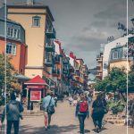 People walking up street between colourful buildings of Mont Tremblant Quebec with text: Exploring Fall Colours in Quebec and Best Things About Mont-Tremblant in Fall