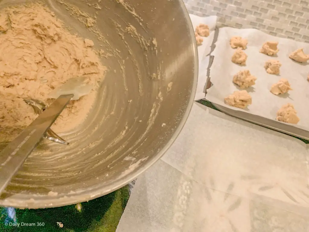 mixing bowl with low carb sugar cookie dough and baking sheets in background