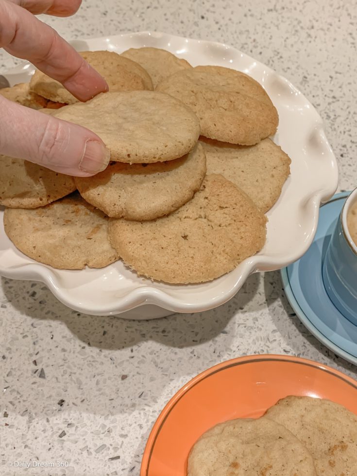 Fingers picking up low carb sugar cookies from plate