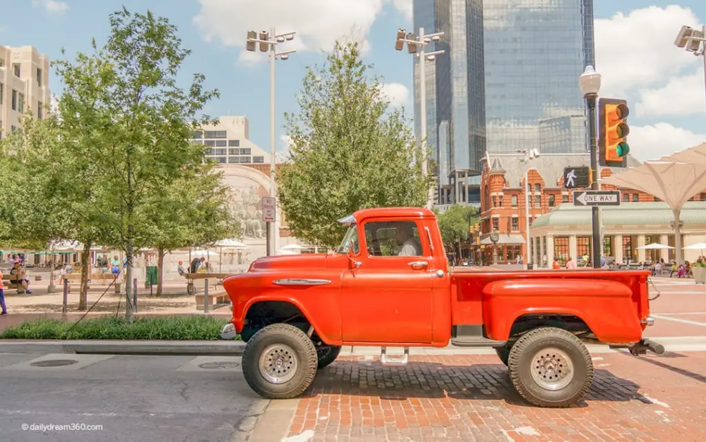 Red truck drive by Sundance square in this image for A Guide of Fun Things to do in Fort Worth Texas