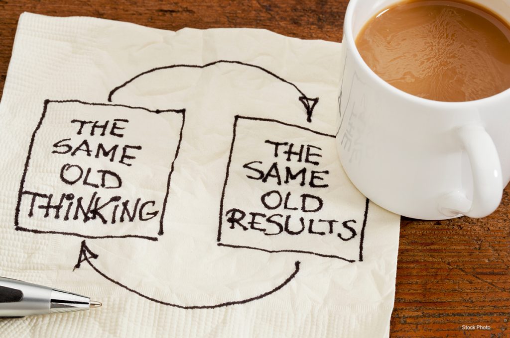 napkin with message same old thinking same old results next to coffee cup