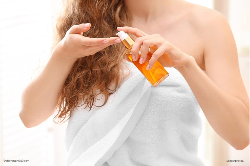 woman wearing towel pumping bath oil into hand