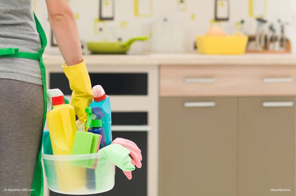 Woman holding cleaning supplies in kitchen