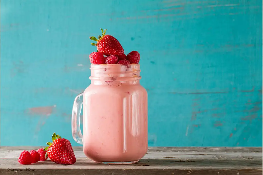 Strawberry smoothie on table with blue wall