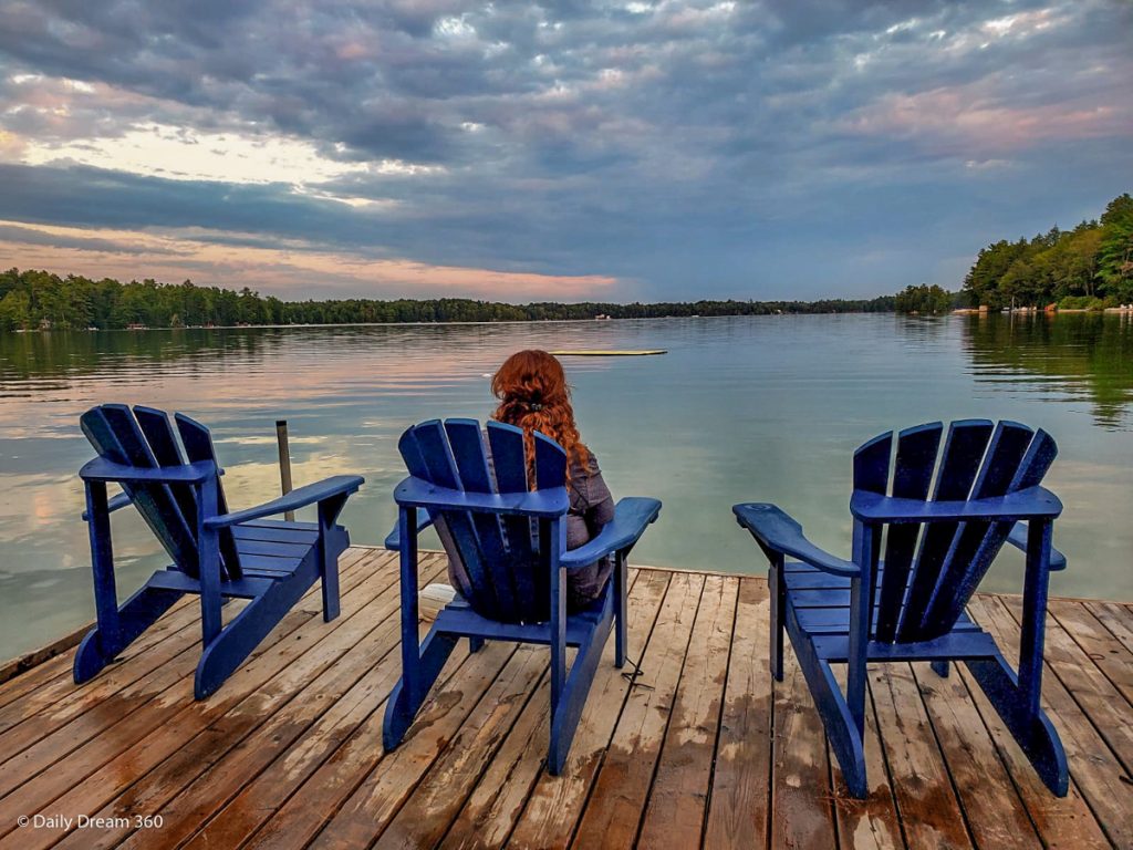 Girl sitting on Adirondack chair on dock over looking the lake at Muskoka Beer Spa