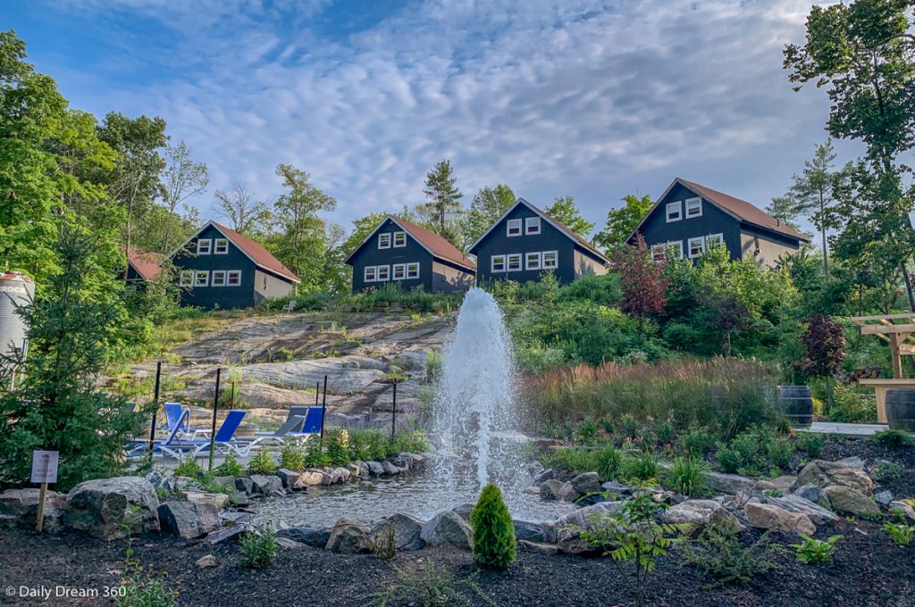 Muskoka Beer Spa Review - Cabins on hill top with water fountain in front