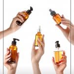 Female hands holding bottles of oil with text: Best Body Oil for Glowing Skin Body Oil Benefits