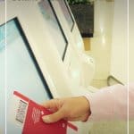 Person checking in at airport self checkin machine with text: Tips for Travelling During Cold and Flu Season