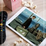 Tablet, popcorn and remote with text List of Travel Inspiration Movies That Will Inspire You to Travel