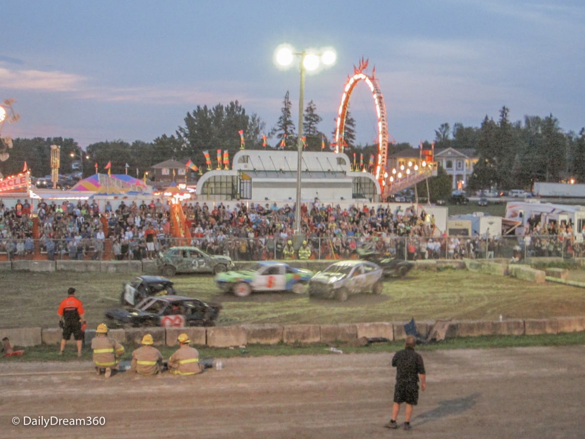 Demolition Derby with midway behind it at Port Perry Agricultural Fair