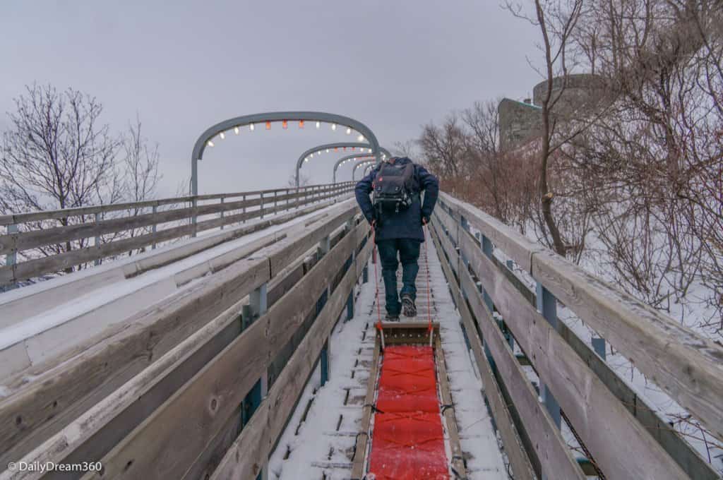 Man walking with wood sled up Quebec City Toboggan Ride