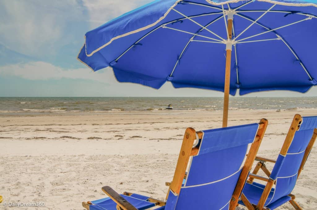 blue lounge chairs under blue umbrella at Sandpiper Gulf Resort Florida