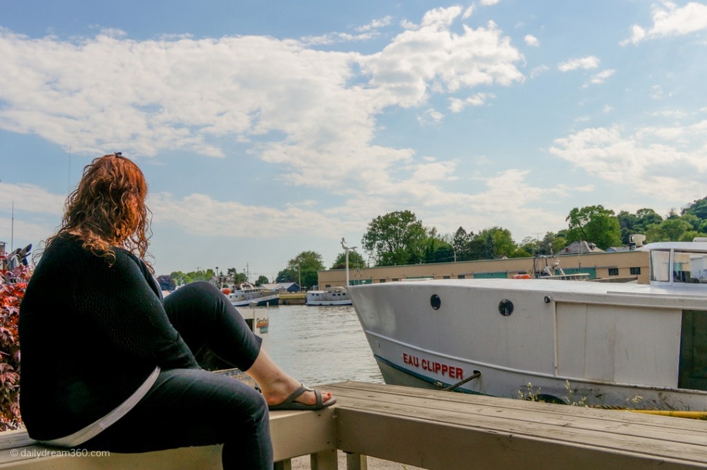 Sharon sitting on waterfront looking at fishing village Port Stanley Ontario Elgin County