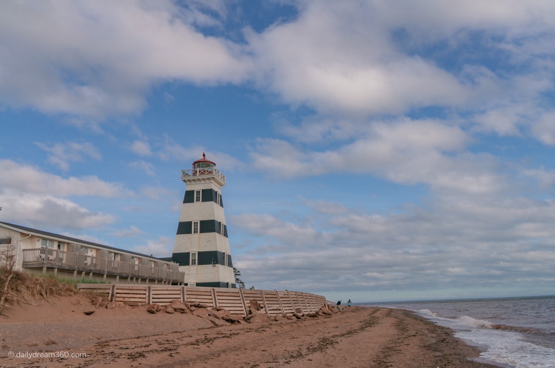 West Point Lighthouse on the beach as waves hit the shore in PEI